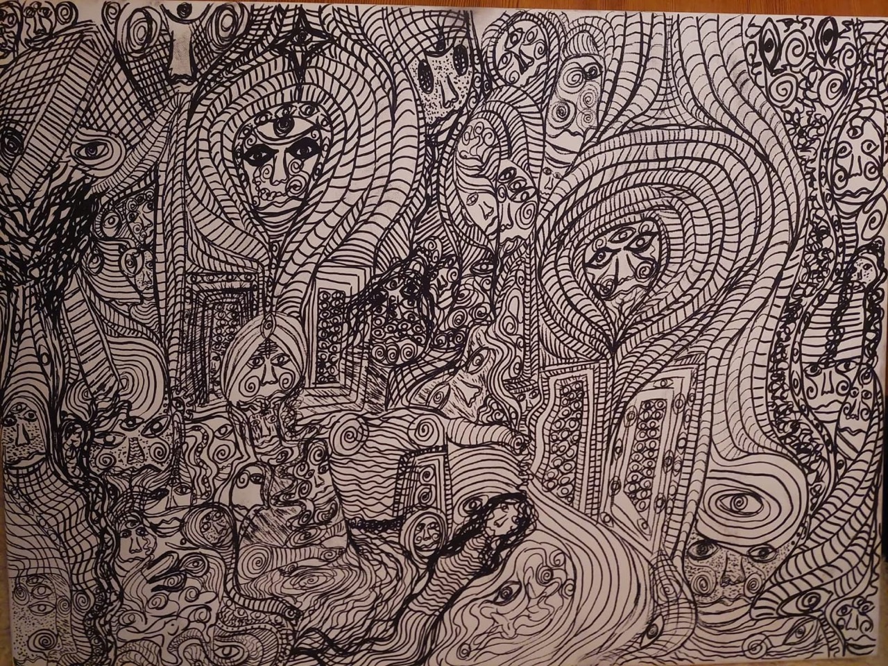 A landscape-format monochrome ink line drawing on a pale ground. A dense all-over field of continuous linework holds many frontal faces and figures, some with a forehead eye motif, among concentric ovals, spirals, arched niches and flowing wave bands. Shown from a working reference photograph.